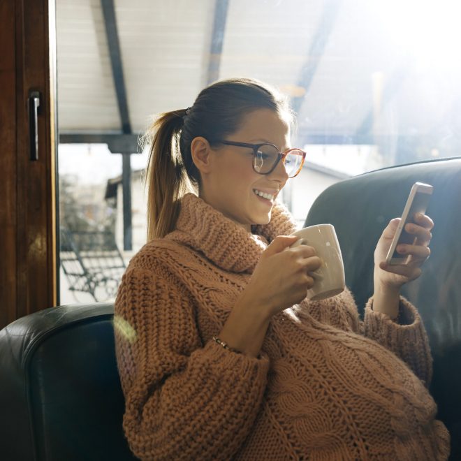 happy pregnant woman enjoying at home and using smartphone